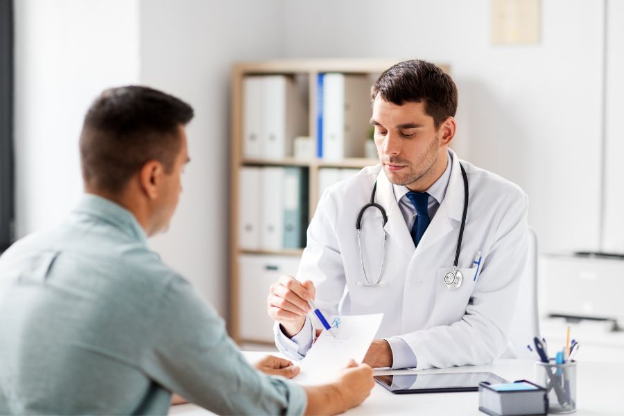 A man talking to a young doctor in his office about his occupational disease.