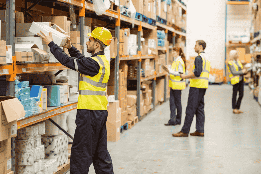 seasonal workers in a warehouse lifting boxes