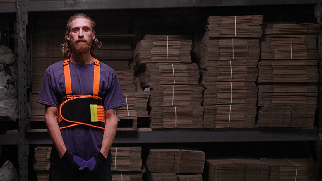 A man wearing a back brace in a warehouse 